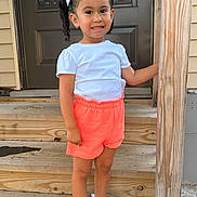 Briana Mora is registered to the contest to win money with this photo: blue_bows, casual_clothing, child, coral_shorts, cute, daylight, door, girl, happy, outdoor, person, pigtails, portrait, post, smile, standing, white_sneakers, white_tshirt, wooden_steps, young
