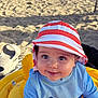baby, beach, clothing, coast, face, footwear, hat, head, lifejacket, nature, outdoors, person, photography, portrait, sea, shoe, summer, sunhat, vest, water
