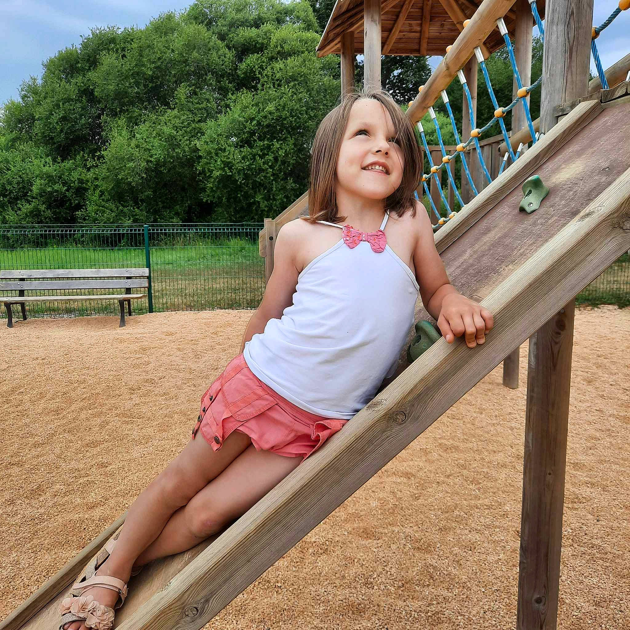 Elise a rejoint le concours — aidez-le/la à gagner de superbes lots ! city, fun, grass, happy, human_leg, joy, leg, leisure, outdoor_play_equipment, people_in_nature, person, pink, plant, recreation, shorts, sitting, sky, smile, t_shirt, thigh
