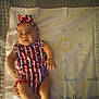 Ka'Lia joined the competition — help win amazing prizes! baby, infant, milestone_blanket, clothing, headband, red_white_blue, stripes, stars, person, child, laying_down, fabric, bed, milestone, months, cute, expression, soft_lighting, indoors, hand