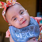 Ka'Lia joined the competition — help win amazing prizes! baby, child, infant, headband, bib, smile, face, person, adult_hand, clothing, portrait, closeup, cute, holding, floral_pattern, colorful, happy, young, people, outdoor