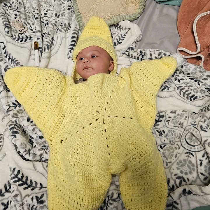 Xavier joined the competition — help win amazing prizes! baby, infant, crocheted_costume, yellow, starfish, blanket, patterned, lying_down, headwear, cozy, soft_texture, indoor, cute, face, child, knitted, wearing, resting, person, young