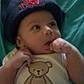 baby, infant, child, hat, navy_blue, onesie, teddy_bear, text, cute, hand, fingers, lying_down, blue_background, clothing, portrait, face, expression, young, adorable, indoor