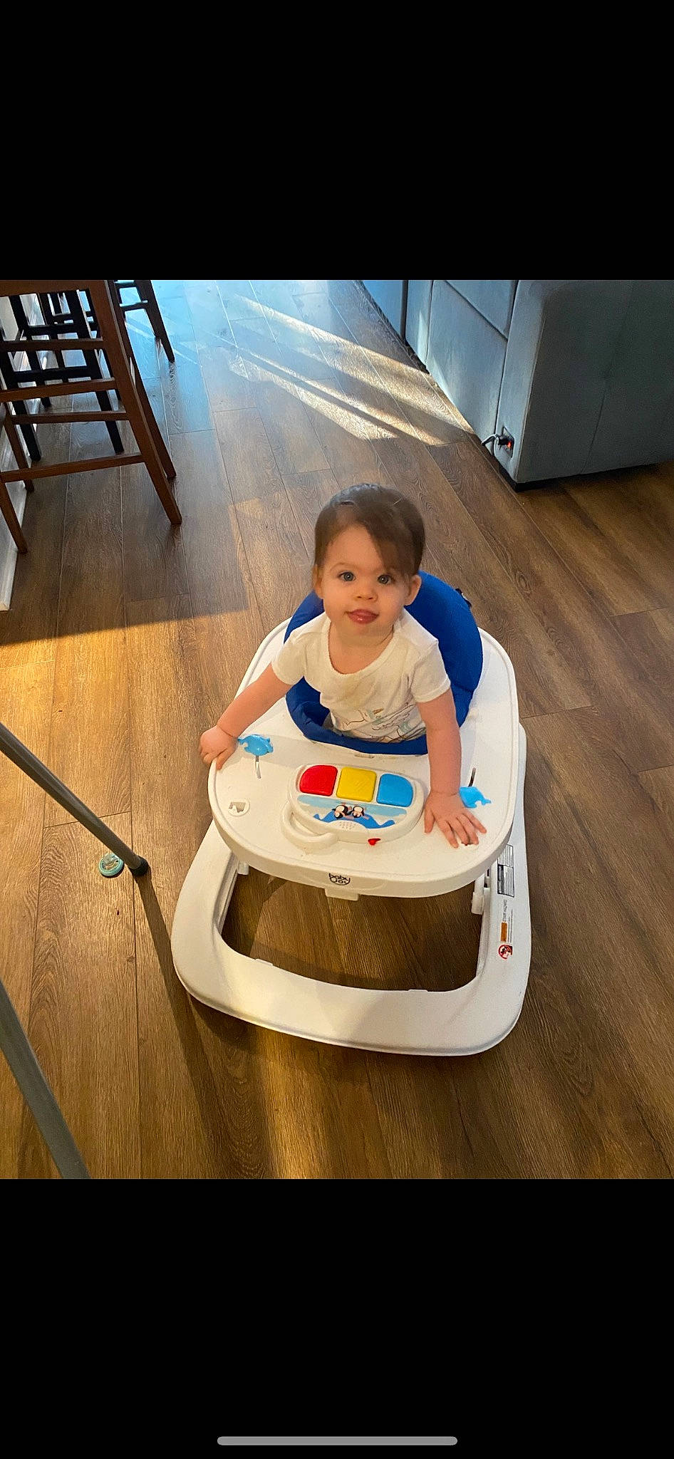 Lillyan is registered to the contest to win money with this photo: baby, baby_products, baby_toddler_clothing, baby_toys, chair, comfort, floor, flooring, fun, happy, hardwood, human_leg, leisure, person, recreation, sitting, smile, t_shirt, thigh, toddler