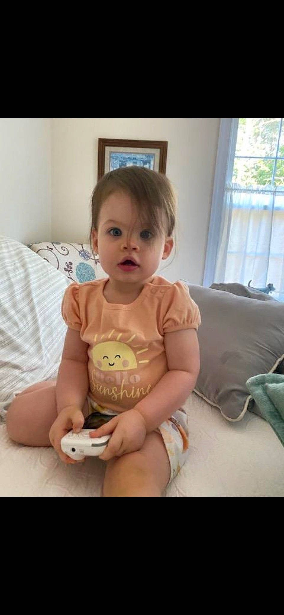 Lillyan is registered to the contest to win money with this photo: baby, baby_toddler_clothing, cheek, child, comfort, face, finger, happy, human_body, human_leg, knee, person, room, sitting, skin, sleeve, t_shirt, thigh, toddler, window