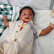 A'Maris is registered to the contest to win money with this photo: baby, infant, playpen, blanket, clothing, wooden_buttons, pacifier_clip, smiling, happy, lying_down, indoor, child, cute, cozy, soft_texture, face, person, expression, arm, toddler