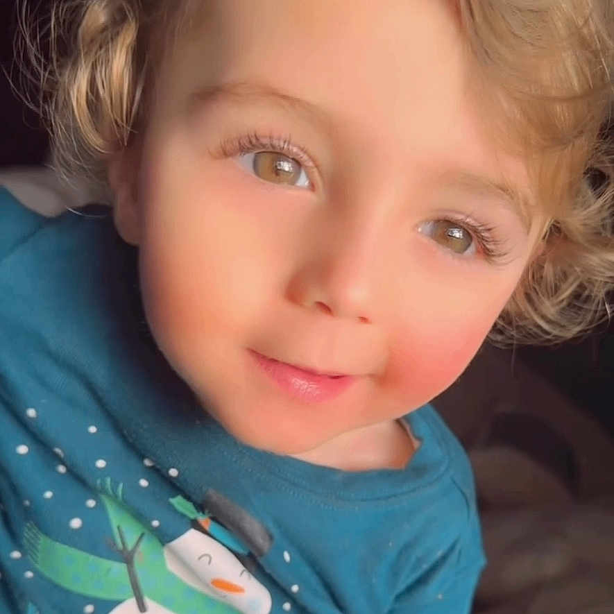 Mahmoud is registered to the contest to win money with this photo: blonde, blue_shirt, brown_eyes, casual_wear, child, closeup, cozy_clothing, curly_hair, cute, face, happy, indoor, person, portrait, rosy_cheeks, smile, snowman_print, soft_light, toddler, young_child