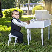 Moisés Iza Tamayo is registered to the contest to win money with this photo: toddler, child, boy, piano, miniature, outdoor, grass, tree, sunlight, smile, suit, white_piano, stool, happy, nature, portrait, music, playing, formal_wear, daylight