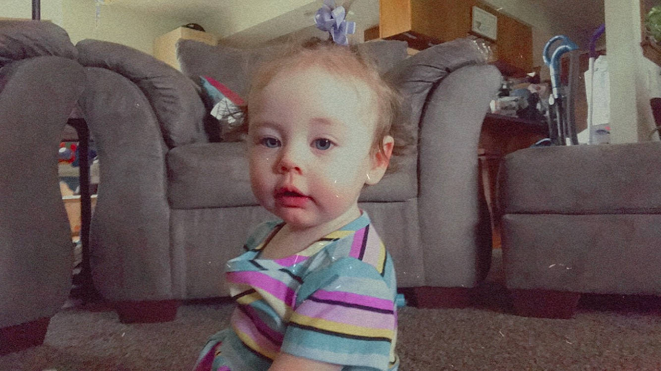 Karma is registered to the contest to win money with this photo: baby, baby_toddler_clothing, chair, cheek, child, comfort, couch, eyebrow, flooring, fun, furniture, lamp, living_room, person, picture_frame, room, sitting, skin, smile, throw_pillow