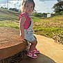 Jazmynn is registered to the contest to win money with this photo: toddler, child, girl, outdoor, grass, cloudy_sky, bench, stone, denim_overalls, pink_shirt, sneakers, sunlight, shadow, curious_expression, shorts, casual_clothing, nature, daytime, young_child, portrait