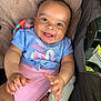 baby, smiling, child, infant, stroller, milk_bottle, toy, clothing, blue_shirt, pink_diaper_cover, happy, cute, face, hands, furniture, seat, portrait, indoors, person, baby_girl