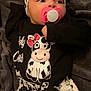 baby, infant, pacifier, headband, cow_pattern, black_clothing, white_clothing, blanket, lying_down, cute, child, soft_texture, sleepwear, portrait, newborn, comfort, resting, indoors, young_child, animal_print
