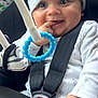 baby, child, car_seat, seatbelt, hat, pajamas, smiling, finger_in_mouth, toy_ring, blue_beads, closeup, cute, infant, safety, car_interior, happy, hand, face, headwear, seated