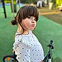 Mía a rejoint le concours — aidez-le/la à gagner de superbes lots ! child, playground, bicycle, polka_dot, white_shirt, outdoor, green_surface, park, cute, playful, face, person, young, hair, fringe, long_sleeve, toy, fun, expression, casual