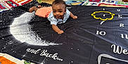 Jalen And David is registered to the contest to win money with this photo: baby, bedroom, celebration, child, colorful_blanket, curious_expression, cute, indoor, infant, lying_down, milestone_blanket, moon, one_month, orange_shorts, patterned_shirt, person, portrait, smiling, stars, yellow_frame