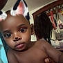 baby, child, face_filter, cat_ears, indoor, portrait, curious, hand, mirror, reflection, furniture, room, young_child, skin, expression, person, cute, closeup, holding, playful