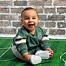 Zylan joined the competition — help win amazing prizes! baby, brick_wall, carpet, casual_clothing, child, cute, face, floor, green_sweatshirt, happy, indoor, person, playful, portrait, sitting, smiling, soccer_field, sports_theme, white_shoes, young