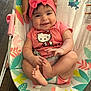 animal_pattern, baby, baby_bouncer, child, colorful, cute, feet, hands, happy, headband, hello_kitty, indoor, infant, leaf_pattern, pattern, person, pink_clothing, portrait, smile, wooden_floor