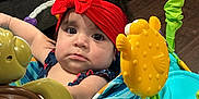 Rilah is registered to the contest to win money with this photo: activity_center, baby, blue, child, colorful, cute, expression, face, floor, furniture, green, indoor, infant, person, play, red_headband, sea_creatures, sitting, toys, yellow