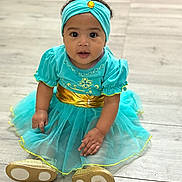 Anylah Brinson is registered to the contest to win money with this photo: baby, child, toddler, sitting, dress, headband, gold, turquoise, floor, curly_hair, indoors, cute, portrait, looking_at_camera, small_shoes, hand, skin, young, fashion, happy