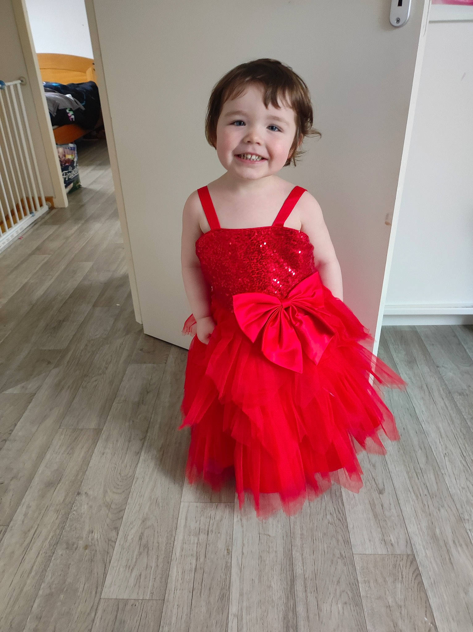 Chloé participe au concours pour gagner de l'argent avec cette photo : baby_toddler_clothing, bridal_party_dress, day_dress, door, dress, fashion_design, floor, flooring, formal_wear, happy, hardwood, joy, laminate_flooring, one_piece_garment, person, skin, sleeve, smile, toddler, waist