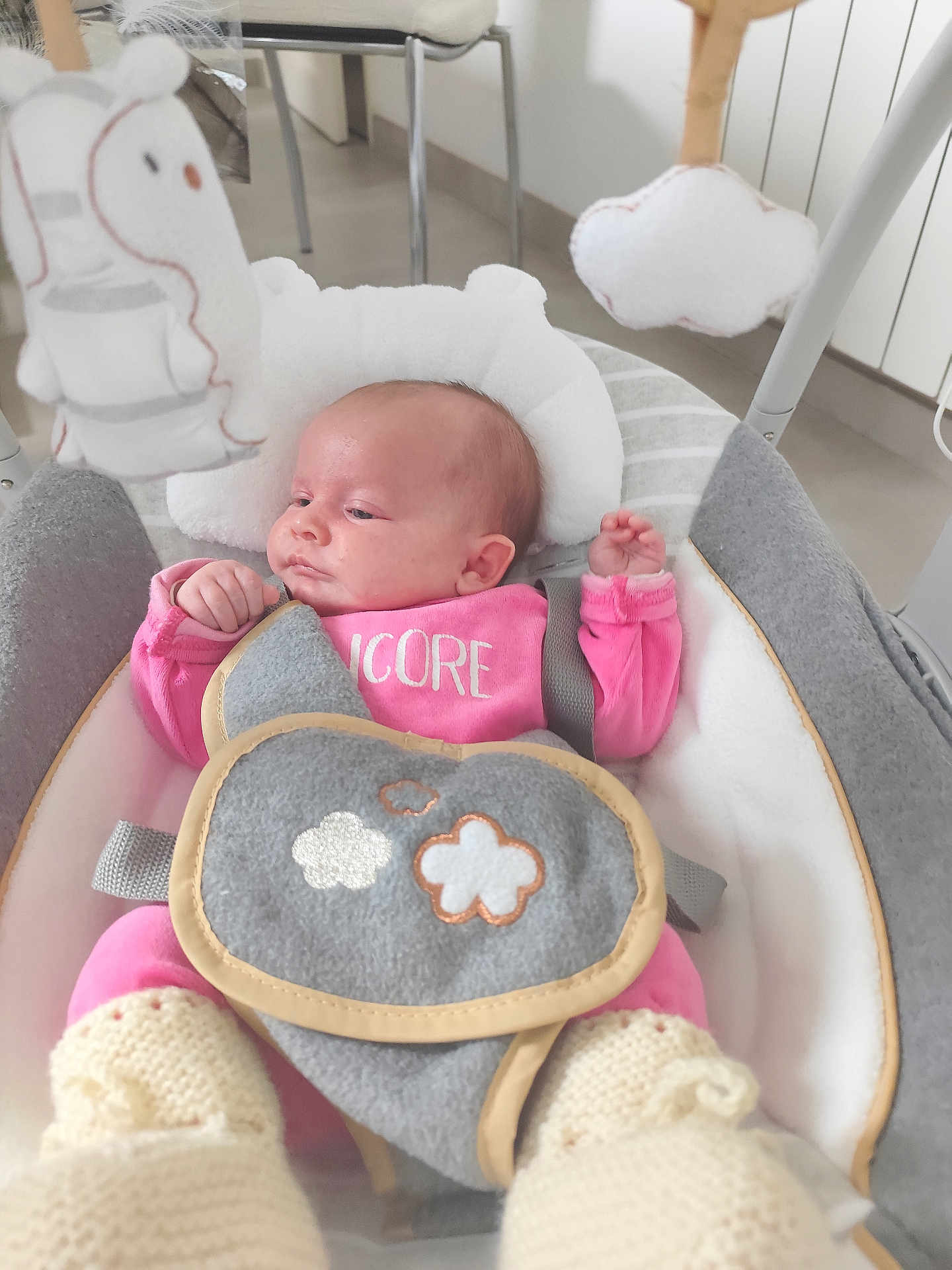 Emma participe au concours pour gagner de l'argent avec cette photo : baby, infant, pink_clothing, baby_rocker, soft_toy, hanging_toy, cushion, knitted_booties, indoor, child, face, person, seat, comfort, cute, resting, newborn, baby_accessory, home, relaxation