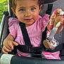 baby, beaded_toy, child, curly_hair, cute, face, green_grass, hand, happy, outdoor, person, pink_clothing, playful, portrait, seat, seatbelt, smiling, stroller, sunlight, toddler