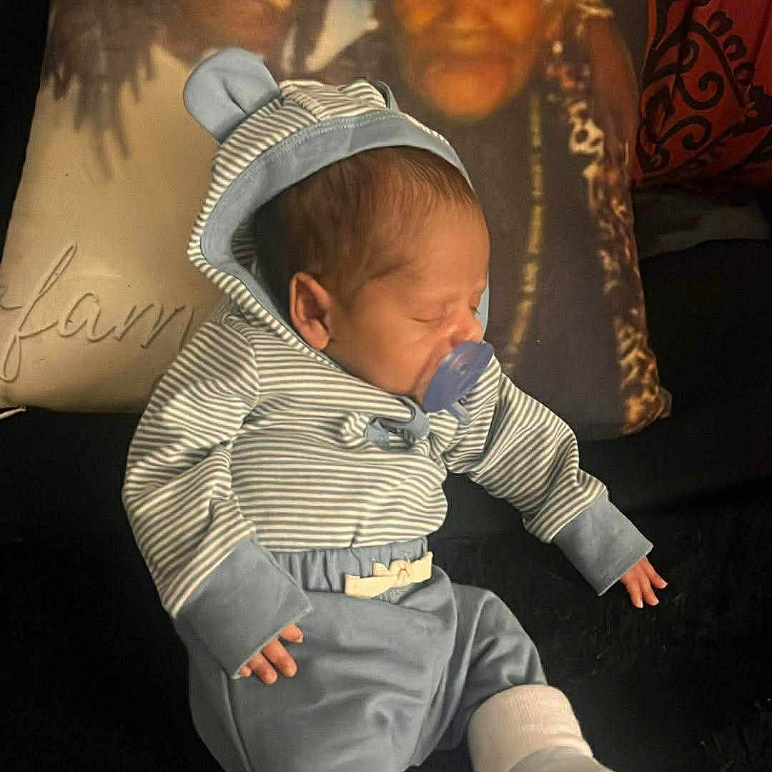 Tyquan is registered to the contest to win money with this photo: baby, blanket, blue_clothing, child, cozy, cute, family_photo, indoor, infant, newborn, pacifier, pillow, portrait, resting, sleeping, smiling_faces, soft_lighting, striped_clothing, warm, white_socks