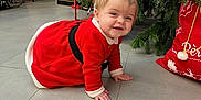 Marion participe au concours pour gagner de l'argent avec cette photo : baby, celebration, child, christmas, christmas_tree, crawling, cute, decor, festive, floor, holiday, holiday_decorations, indoors, nutcracker, person, pigtails, red_dress, smiling, stocking, tiled_floor