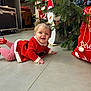 Marion participe au concours pour gagner de l'argent avec cette photo : baby, child, christmas_sack, christmas_tree, cute, decorations, festive_clothing, floor, happy, holiday, indoor, person, pigtails, playful, red_clothing, seasonal, smiling, sock, striped_socks, toy