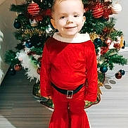 Luna participe au concours pour gagner de l'argent avec cette photo : child, christmas_tree, holiday, festive_clothing, red_outfit, smiling, indoors, decorations, ornaments, greenery, flooring, sneakers, happy, celebration, seasonal, holiday_spirit, young_child, portrait, christmas, tree_lights