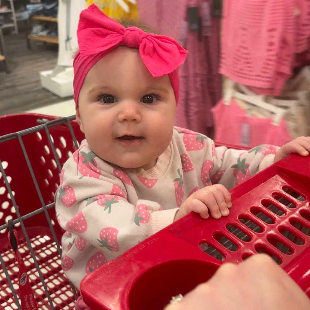 Presley joined the competition — help win amazing prizes! baby, child, shopping_cart, headband, pink_bow, clothing_store, clothes, rack, shopping, cute, infant, portrait, smiling, hand, retail, indoor, person, apparel, store, toddler