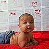 baby, infant, kiss_marks, red_blanket, jeans, face, arm, back, heart_drawings, xoxo_text, printed_pages, lying_down, cute, adorable, skin, chubby, portrait, indoor, love, playful