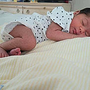 Grace is registered to the contest to win money with this photo: newborn, baby, sleeping, infant, onesie, star_pattern, blanket, bedroom, soft_lighting, curled_up, peaceful, indoors, furniture, dresser, skin, face, foot, hand, resting, cozy
