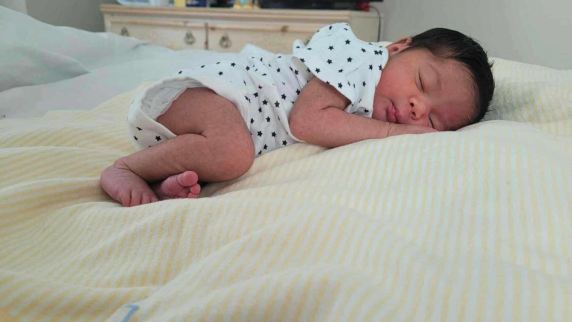 Grace is registered to the contest to win money with this photo: newborn, baby, sleeping, infant, onesie, star_pattern, blanket, bedroom, soft_lighting, curled_up, peaceful, indoors, furniture, dresser, skin, face, foot, hand, resting, cozy