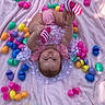baby, infant, child, blanket, pink_blanket, easter_eggs, colorful_eggs, toy, outdoor, grass, playful, cute, smiling, clothing, striped_socks, reaching, lying_down, sunlight, happy, portrait
