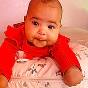 Yazlyn is registered to the contest to win money with this photo: baby, blanket, cheeks, child, cozy, curious, cute, eyes, face, hands, home, indoor, infant, lying_down, pattern, pillow, portrait, red_clothing, soft, young