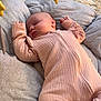 baby, sleeping, onesie, pink_clothing, plush_toys, star_toy, moon_toy, cushion, soft_fabric, carpet, indoor, child, infant, nap, cozy, peaceful, person, toddler, bedroom, rest