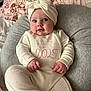 Lottie joined the competition — help win amazing prizes! baby, infant, headband, bow, cushion, pillow, blanket, clothing, onesie, face, person, portrait, indoors, soft_furniture, cute, smiling, child, cozy, resting, comfortable