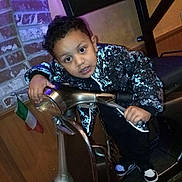 Khristine Spencer joined the competition — help win amazing prizes! child, boy, jacket, scooter, indoor, brick_wall, flag, metal, toy_vehicle, curly_hair, casual_clothing, young, playful, grip, person, floor, lighting, expression, handlebars, shoes