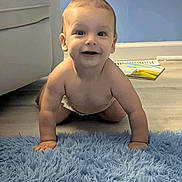 Spencer is registered to the contest to win money with this photo: baby, crawling, blue_rug, smiling, indoor, child, floor, carpet, happy, skin, diaper, person, furniture, home, head, arm, hand, flooring, wall, room