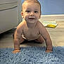 baby, crawling, blue_rug, smiling, indoor, child, floor, carpet, happy, skin, diaper, person, furniture, home, head, arm, hand, flooring, wall, room