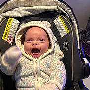 Zaryah is registered to the contest to win money with this photo: baby, infant, car_seat, jacket, mittens, happy, smiling, child, cozy, warm_clothing, indoor, person, cute, apparel, seat, expression, joyful, cute_baby, hood, face