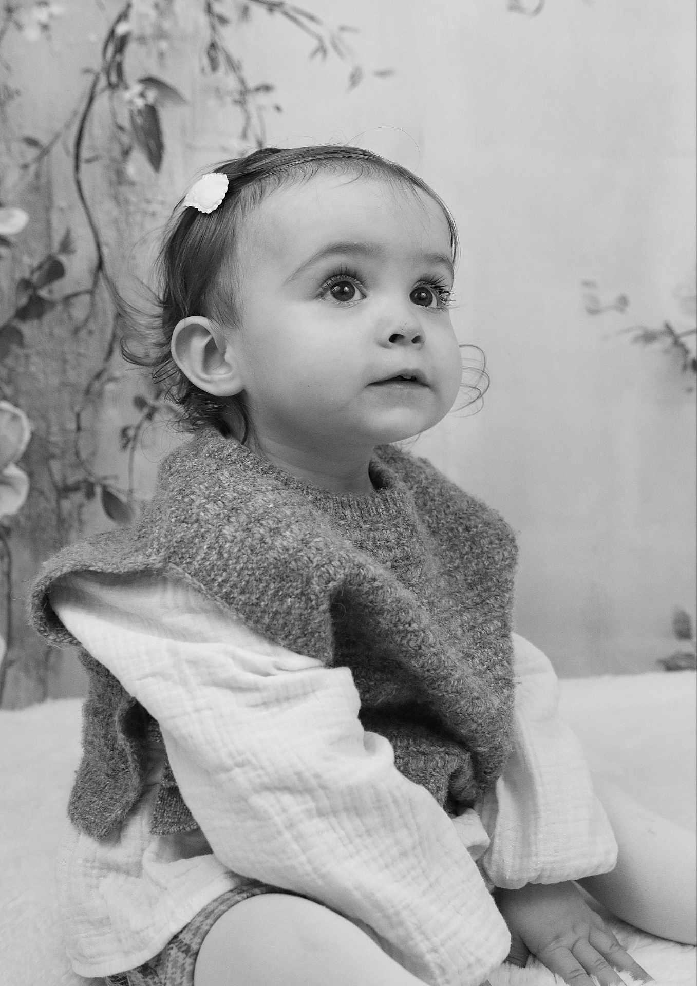 Adèle participe au concours pour gagner de l'argent avec cette photo : toddler, child, portrait, black_and_white, knitted_vest, hair_clip, curious, sitting, soft_light, indoors, long_sleeve, young_child, face, expression, cute, cozy, closeup, baby, person, innocence
