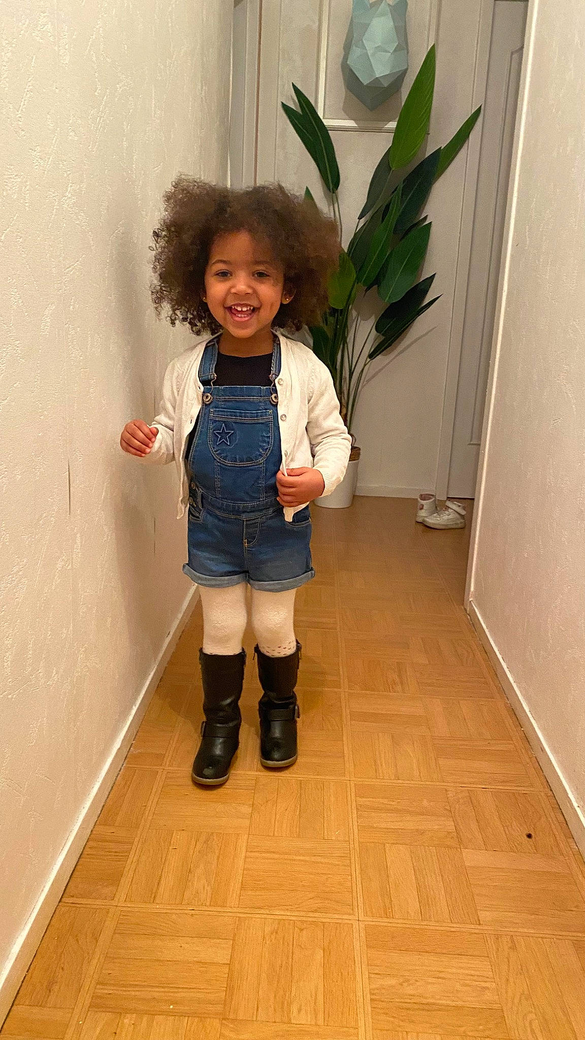 Maeva participe au concours pour gagner de l'argent avec cette photo : boot, eye, fashion_design, floor, flooring, happy, hardwood, houseplant, human_leg, joy, knee, leg, person, plant, smile, sneakers, sock, thigh, toddler, uniform