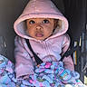 baby, child, hood, pink_clothing, blanket, unicorn_pattern, stroller, seatbelt, cute, portrait, infant, warm_clothing, expression, eyes, face, bundle, cozy, colorful, pattern, sitting