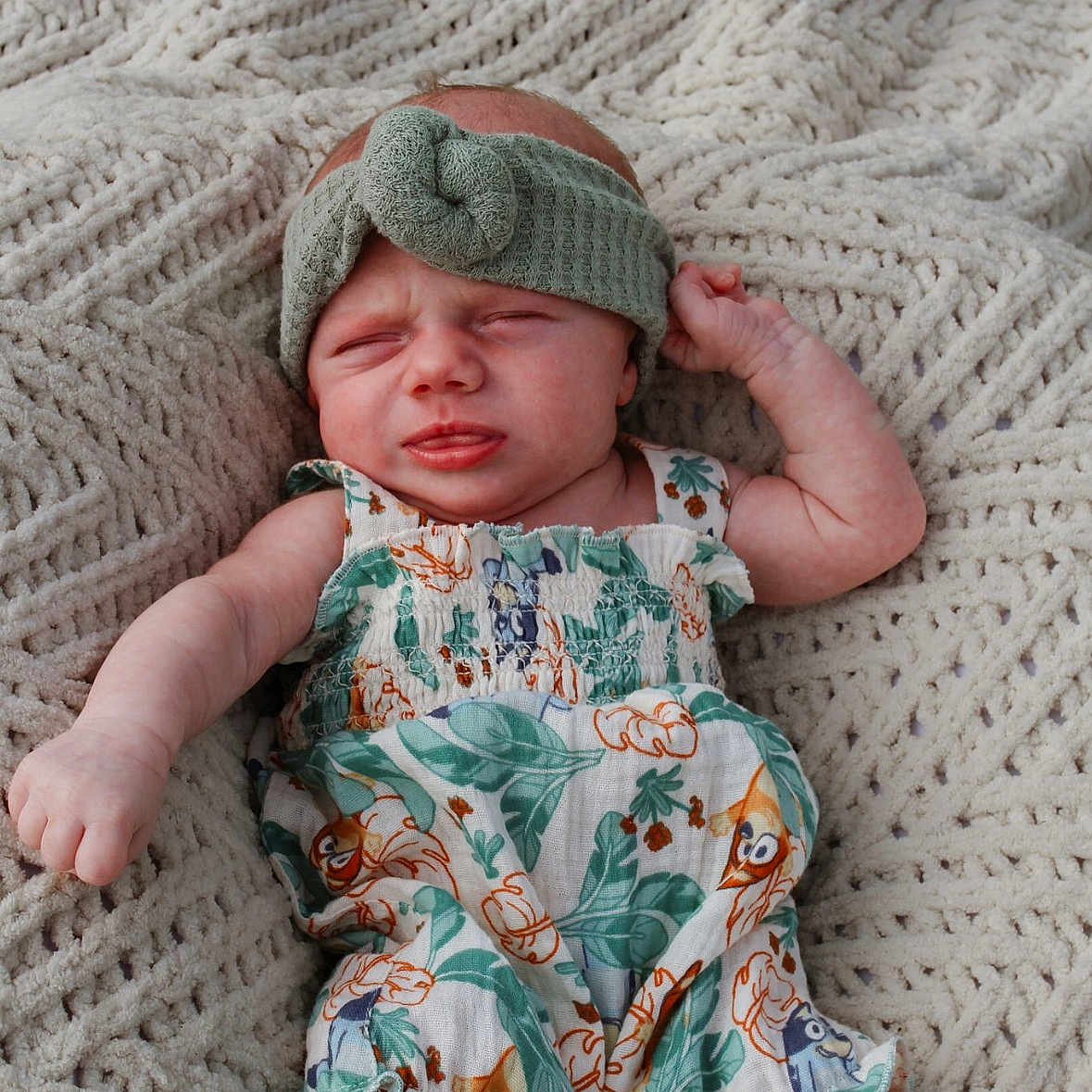 Emilynn joined the competition — help win amazing prizes! baby, blanket, clothing, cozy, cute, expression, face, foot, hand, headband, indoors, infant, lying_down, newborn, pattern, portrait, romper, skin, sleepwear, texture