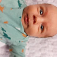 Mathias ștefan participe au concours pour gagner de l'argent avec cette photo : baby, infant, face, blur, closeup, child, clothing, green_outfit, pattern, lying_down, skin, head, eyes, mouth, newborn, person, indoors, soft_focus, young, human