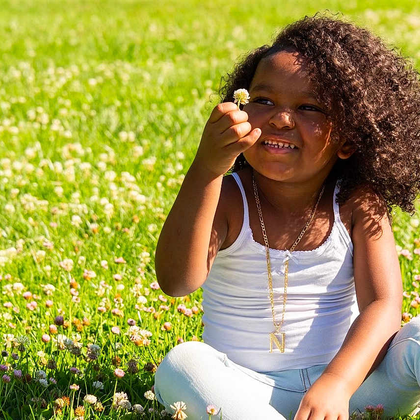 Kamari is registered to the contest to win money with this photo: accessories, child, face, female, flower, girl, grass, hair, happy, head, jewelry, lawn, necklace, outdoors, person, photography, plant, portrait, sitting, smile
