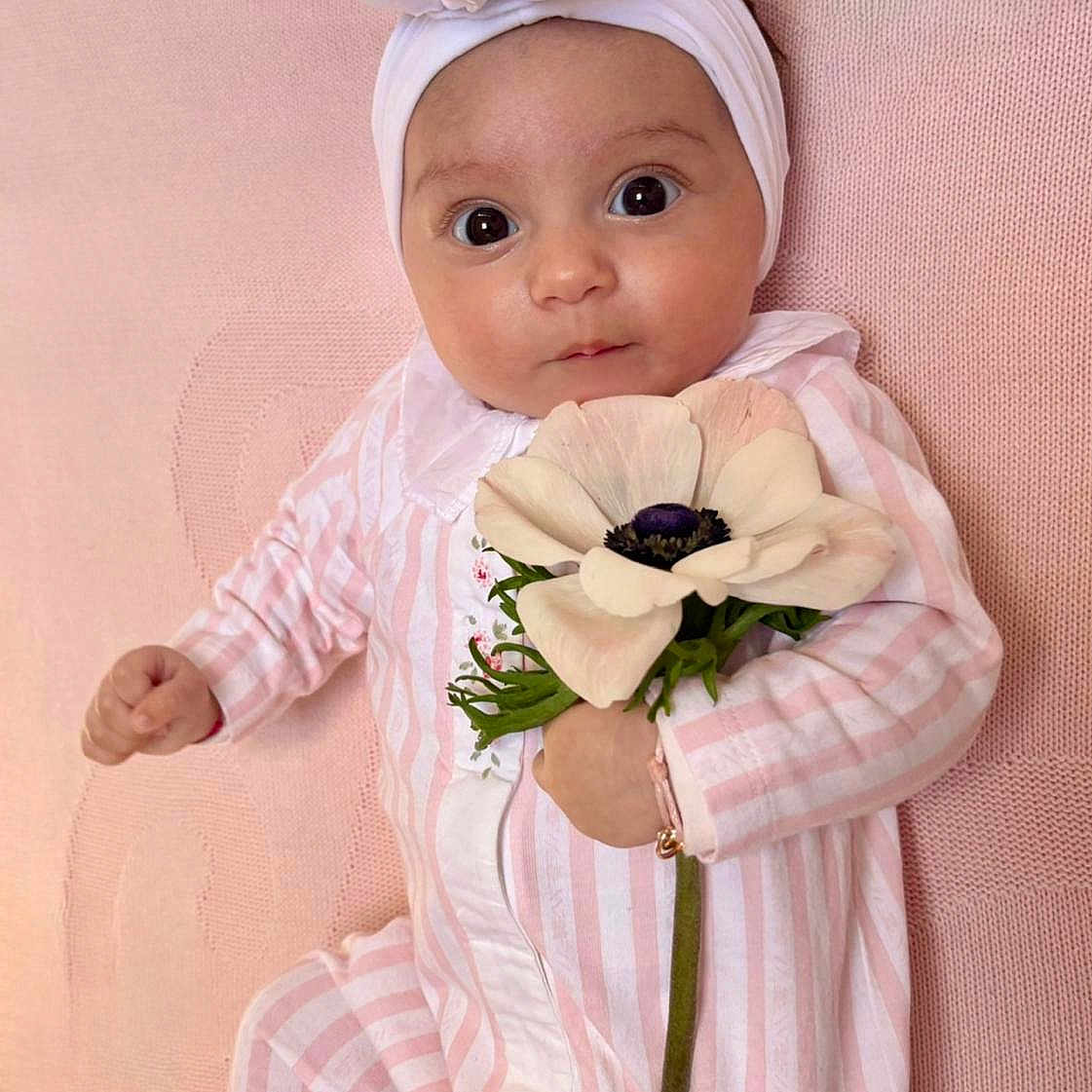 Naël a rejoint le concours — aidez-le/la à gagner de superbes lots ! baby, infant, flower, headband, pink, striped_clothing, blanket, cute, portrait, child, young, laying_down, soft_texture, adorable, closeup, big_eyes, hand, white_flower, headwear, sleepwear
